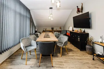 a dining room with a table and chairs and a tv at Вила Тих кът in Resilovo