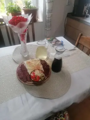 a table with a plate of food and a vase of flowers at Къща Сливови in Bŭnzareto