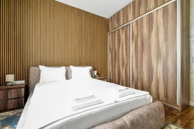 a bedroom with a large bed and a wooden wall at Blue Breeze Apartment by Flat Mаnager in Sofia