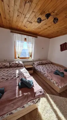 two beds in a room with a large window at Вила Зора in Chepelare