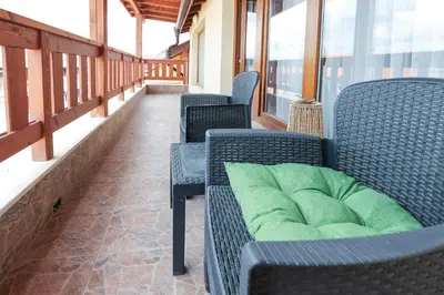 a porch with chairs with a green pillow on it at Bansko 1BR for 4 w Balcony View Spa Near Ski Lift in Bansko