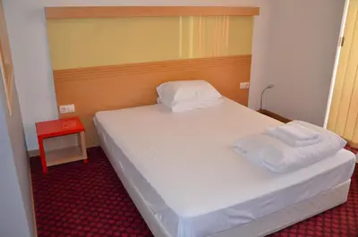 a small bedroom with a bed with two towels on it at Хотел Летище Лесново in Ormanliya