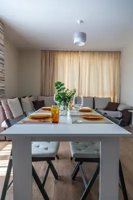 a white dining room table with chairs and a couch at Просторен апартамент за семейна почивка in Hisarya