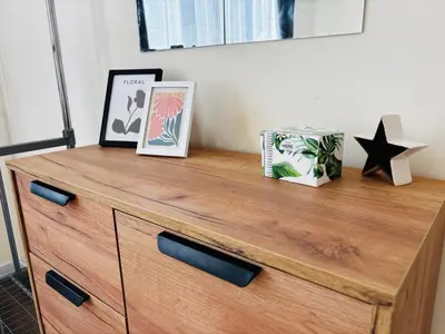 a wooden dresser with two pictures on top of it at Spacious&Cousy 3 bedroom apartment in Plovdiv
