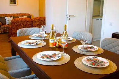 a wooden table with plates and wine glasses on it at Bright & Cozy Apartment for 4 Guests in Plovdiv Centre in Plovdiv
