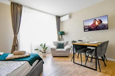 a bedroom with a bed and a table and a tv at Sunny Sofia Studio with Balcony by Flat Mаnager in Sofia