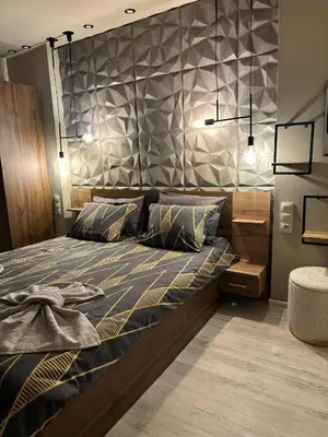 a bedroom with a large bed with a stone wall at Къща за гости Рилски чардак in Sapareva Banya