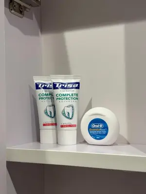 a shelf with three containers of toothpaste and a clock at Apartment Hristina in Dobrinishte