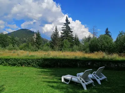 two white chairs sitting in the grass in a field at Oxygen Time in Smolyan