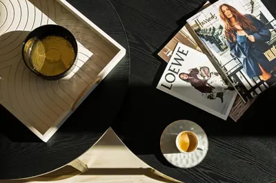 a table with a book and a cup of coffee and magazines at Einik Luxury Apartments in Velingrad