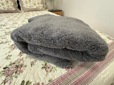 a gray blanket sitting on top of a bed at Apartament Avangard in Pazardzhik