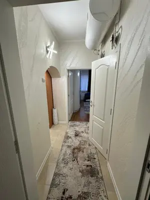 a hallway with a white door and a rug at Apartament Avangard in Pazardzhik