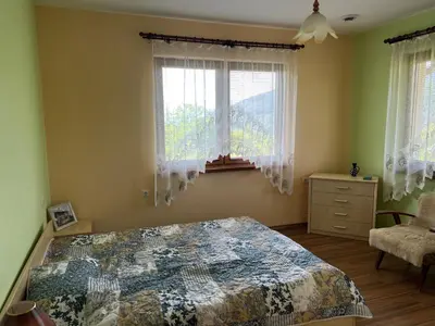 a bedroom with a bed and two windows and a chair at The Old Walnut House in Terziysko