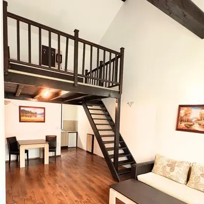 a staircase in a living room with a couch and a table at Everwood Hotel & Restaurant in Govedartsi