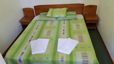 a bed with green sheets and white pillows at Boeritza Hotel Complex in Vladaya