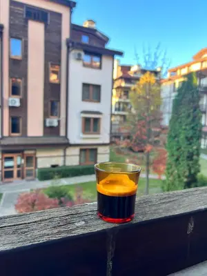 a drink sitting on a ledge with a view of a city at Downtown Bansko Resort in Bansko
