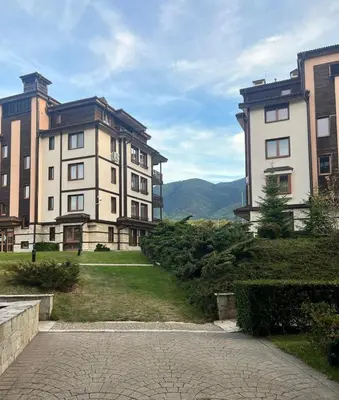 a group of buildings with mountains in the background at Downtown Bansko Resort in Bansko
