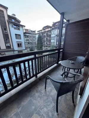 a balcony with a table and a chair on a balcony at Downtown Bansko Resort in Bansko