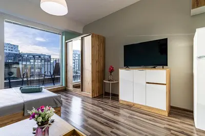 a living room with a tv and a large window at Student City Studio With Mountain View Balcony and Underground Parking 1 in Sofia