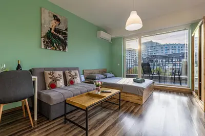 a living room with a couch and a table at Student City Studio With Mountain View Balcony and Underground Parking 1 in Sofia