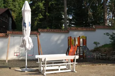 a white bench and an umbrella next to a playground at Лари Б01 in Borovets