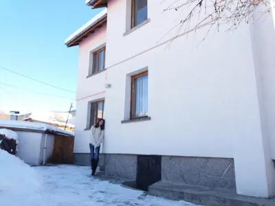 a woman standing on the side of a white building at Guest House AHP in Mala Tsŭrkva