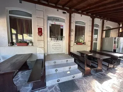 a patio with two benches and a table and a door at Семеен хотел Модерния хан in Zărkwischte