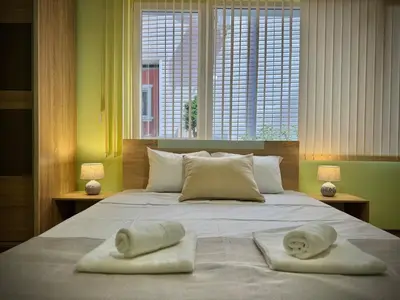 a bedroom with two towels on a bed with two windows at City Modern & Cozy Apartment for 4 Guests in Sofia, Lozenets in Sofia