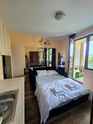 a bedroom with a large bed and a sink at Апартамент- Студио Кокетно in Sandanski