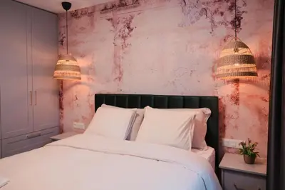 a bedroom with a bed with white sheets and two lamps at Quiet & Stylish Apartment in Central Sofia in Sofia