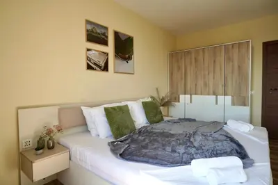 a bedroom with a large white bed with green pillows at Cozy place with free parking in Sofia