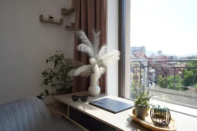 a desk with a laptop and a window with a view at Cozy place with free parking in Sofia