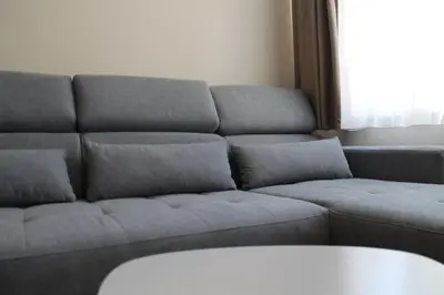 a gray couch in a living room with a window at cosy apartment in Sofia