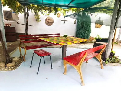 a picnic table and two benches under a tent at Самостоятелна къща за гости Трояна in Troyan