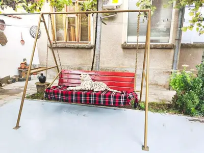 a white cat sitting on a swing at Самостоятелна къща за гости Трояна in Troyan