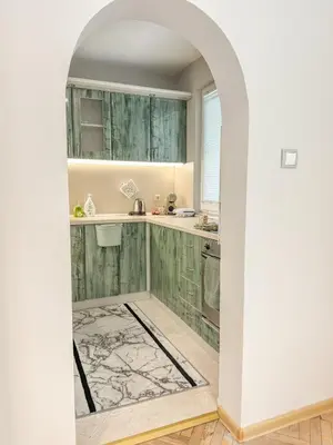an arched doorway into a kitchen with green cabinets at Two-Bedroom Central and Cosy Apartment in Plovdiv