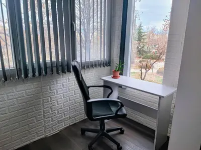 a desk and a chair in a room with a window at Sunny Corner Apartment in Plovdiv