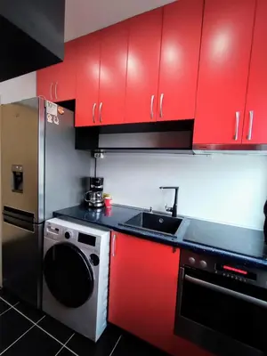 a kitchen with red cabinets and a sink and a dishwasher at Sunny Corner Apartment in Plovdiv