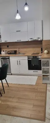 a kitchen with white cabinets and a wooden floor at Green apartment Velingrad in Velingrad