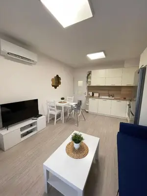 a living room with a table and a kitchen at Well Equipped New Family Friendly One-Bedroom Flat in Sandanski