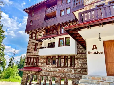 a house in the mountains with a wooden door at Tulip Studio Deluxe, Grand Resort Pamporovo in Pamporovo
