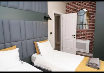 a bedroom with two beds and a brick wall at FS Apartments Kapana Boutique Family Stay in Plovdiv