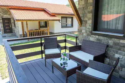 a deck with two chairs and a table with a table at Двете къщи село Бели осъм in Beli Osŭm