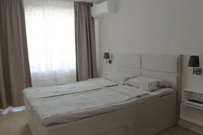 a white bed in a bedroom with a window at cosy apartment in Sofia
