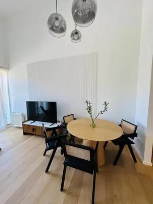 a living room with a table and chairs and a television at White & Wood Suite C302, at Euphoria SPA Borovets in Borovets
