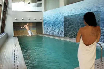 a woman watching a boy in a swimming pool at White & Wood Suite C302, at Euphoria SPA Borovets in Borovets