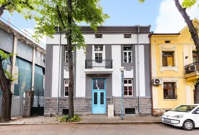 a white building with a blue door on a street at Apt Kosmos in the best Central Area in Plovdiv in Plovdiv