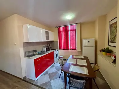 a kitchen with red cabinets and a table and a refrigerator at Comfy Apt next to Palace of Justice in Sofia
