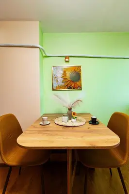 a wooden table in a room with chairs and a painting at Sunflower Studio next to Kolodrum Plovdiv in Plovdiv