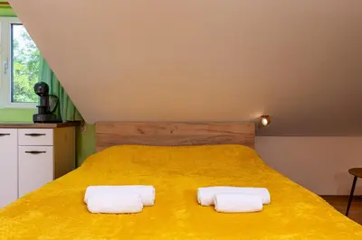 a bedroom with a large yellow bed with two towels at Sunflower Studio next to Kolodrum Plovdiv in Plovdiv